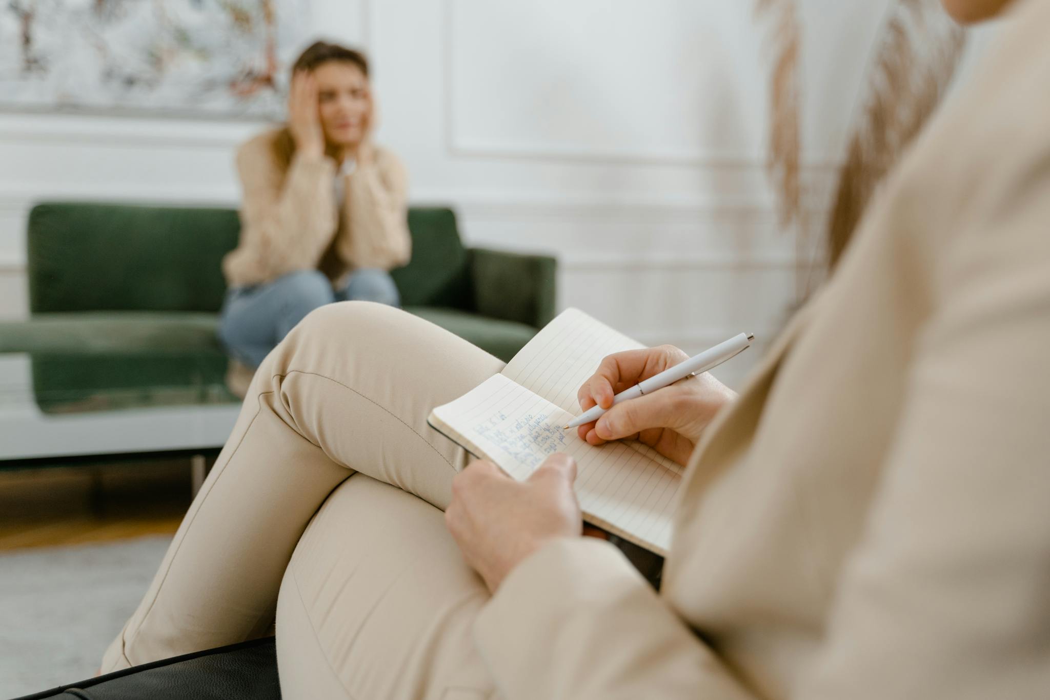 A therapist taking notes during a consultation with a patient, focusing on mental health.